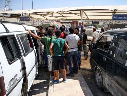 Refugiados sirios, deportados desde Turquía, suben a minibuses en la puerta fronteriza de Bab al-Hawa (Idlib) para dirigirse a diversas partes de Siria.