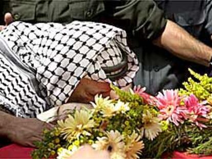 Yasir Arafat besa la bandera nacional palestina que cubre el féretro de Faisal Huseini, ayer, en Ramala.