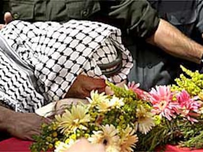 Yasir Arafat besa la bandera nacional palestina que cubre el féretro de Faisal Huseini, ayer, en Ramala.