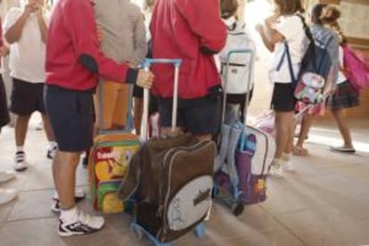 Varios niños llegan con sus mochilas al colegio