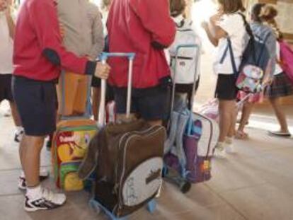 Varios niños llegan con sus mochilas al colegio
