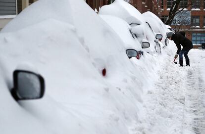Una vecina del barrio de Charlestown (Boston) retira la nieve de su coche. La tormenta ha dejado varios metros de altura a su paso por la capital.