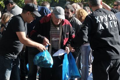 Miembros del partido neonazi Amanecer Dorado reparten comida en una plaza de Atenas.
