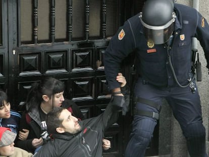 Un agente desaloja de la puerta de una vivienda de Torrejón (Madrid), a las personas concentradas para apoyar a un desahuciado.