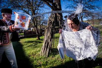 Un hombre vestido con un traje tradicional arroja un cubo de agua sobre una mujer como parte de las celebraciones de Pascua de la población de Strelniky (Eslovaquia). 