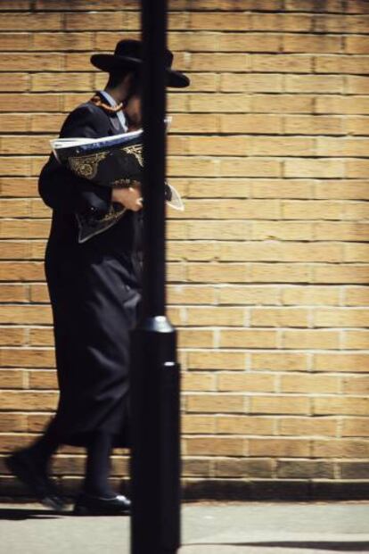 Un miembro de la comunidad judía de Chareidi sale de la sinagoga de Stamford Hill con su Tallit.