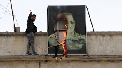 Un hombre hace la se?al de la victoria junto al retrato en llamas del presidente sirio Bachar el Asad, este domingo en la ciudad de Qamishli. 