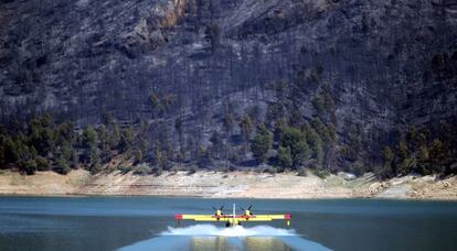 Una de las avionetas del dispositivo de extinción coge agua del pantano para luego sofocar el fuego.