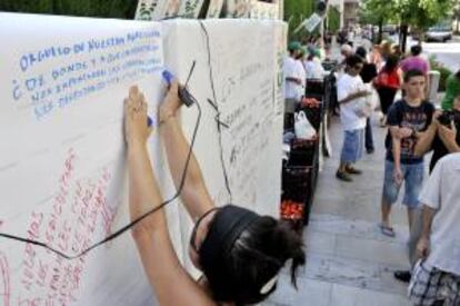 Unas mujer escribe un mensaje de apoyo en el "muro de las lamentaciones" levantado por la Unión de Pequeños Agricultores (UPA) de Andalucía.