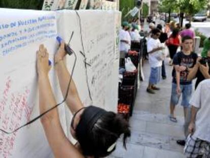 Unas mujer escribe un mensaje de apoyo en el "muro de las lamentaciones" levantado por la Unión de Pequeños Agricultores (UPA) de Andalucía.