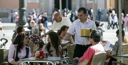 Un camarero sirve bebidas en una terraza en la plaza de la Virgen de Valencia.