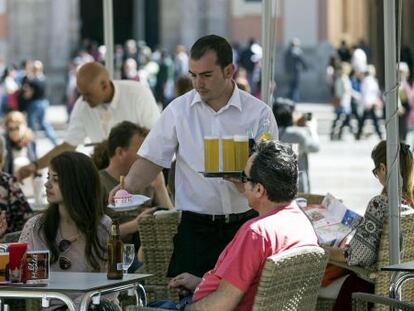 Un camarero sirve bebidas en una terraza en la plaza de la Virgen de Valencia.