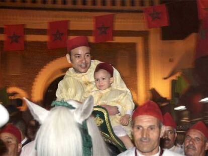 El rey de Marruecos, Mohamed VI, lleva a su hijo en brazos por las calles de Fez, en abril de 2005.