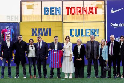 Xavi posa con una camiseta del Barça junto al presidente Joan Laporta y familiares del nuevo técnico, este lunes en el Camp Nou.