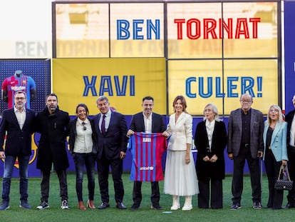Xavi posa con una camiseta del Barça junto al presidente Joan Laporta y familiares del nuevo técnico, este lunes en el Camp Nou.
