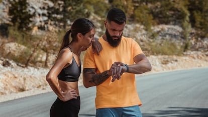 Una pareja preparando el reloj para correr.