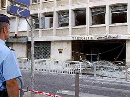 Un policía contempla los daños causados por una bomba en el edificio de la Tesorería y Aduanas de Niza.