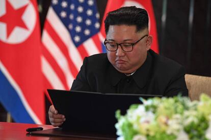 El líder de Korea del Norte, Kim Jong-un mira el documento durante el acto de la firma con el presidente norteamericano, Donald Trump.