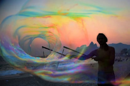 
German tourist Florian plays with bubbles at sunset, in Ipanema beach in Rio de Janeiro on October 13, 2014. AFP PHOTO / CHRISTOPHE SIMON