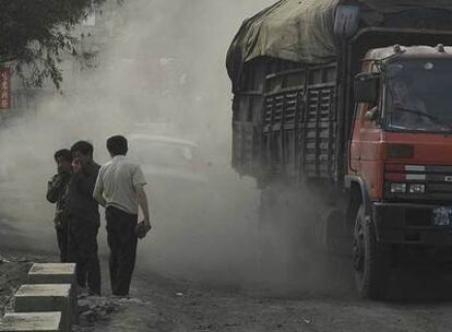 Varios transeúntes cubren sus rostros al paso de un camión cargado de carbón, ayer en el norte de China.