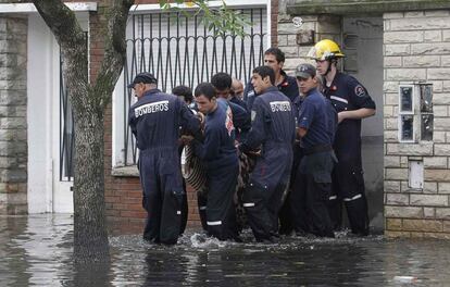 Bomberos rescatan a una persona de su casa inundada tras las fuertes lluvias caídas en la ciudad argentina de La Plata.