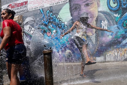 Dos vecinas se refrescaban el viernes con el chorro de agua de una boca de riego, en el Bronx, en Nueva York.