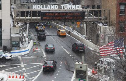 Varios coches se adentran en el túnel Holland. En la parte superior de su entrada, una pantalla alerta sobre las malas condiciones meteorológicas.