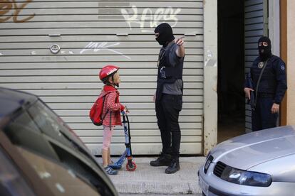 Um agente da alfândega pede a uma criança em patinete que mude de calçada na unidade policial em Terrassa (Barcelona) que desmantelou uma grande plantação de maconha no centro da localidade, em 3 de setembro de 2019.