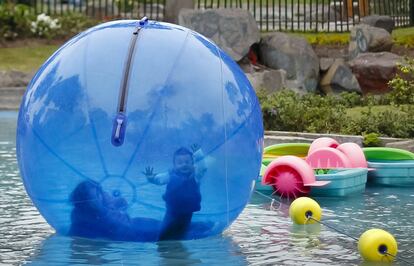 Un niño junto a su madre juega en el interior de una pelota de plástico que flota en el agua en el parque de Lima (Perú), 7 de noviembre de 2013.