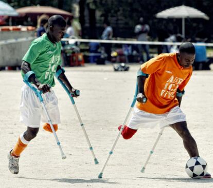 Dos futbolistas sierraleoneses con la pierna cortada, durante el partido que jugaron ayer en la Casa de Campo.