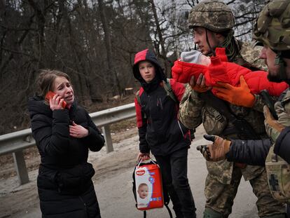 Vlod sostiene a Emma mientras su madre, Julia, intenta localizar a su marido en la huida en Irpin (Ucrania).