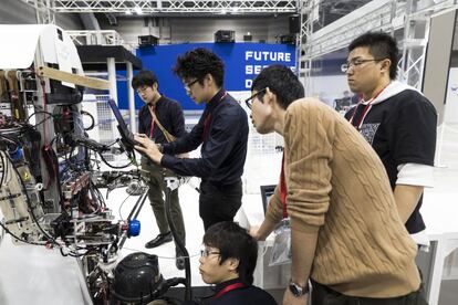 Un grupo de competidores en el World Robot Summit verifica el estado de su robot para el desafío de la feria.