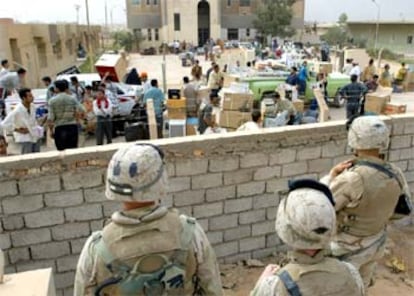 Tres soldados de EE UU observan los saqueos en un suburbio del sudeste de Bagdad.