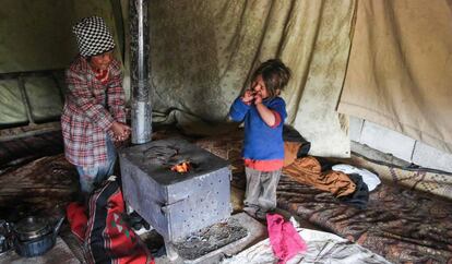 Dos niñas sirias tratan de entrar en calor en un campo de refugiados cercano a Damasco, este miércoles.