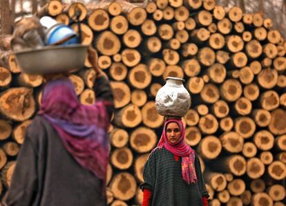 Una mujer lleva una jarra de metal llena de agua potable, en Srinagar (India).