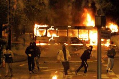 Un grupo de encapuchados se enfrenta a la policía la noche del lunes en Toulouse. Al fondo, arde un autobús.