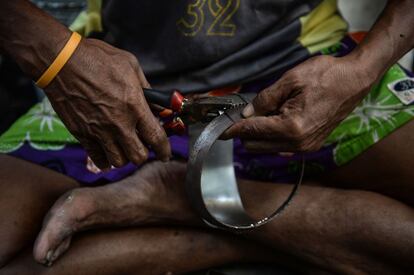 Las manos de un hombre cortando láminas de acero que servirán para fabricar los cuencos de limosna tradicionales budistas para el día de 'Khao Pansa'.