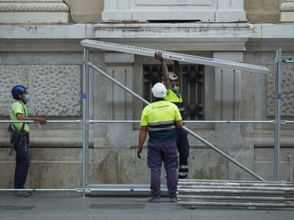 Varios operarios montan un andamio en un edificio del centro de Sevilla.
