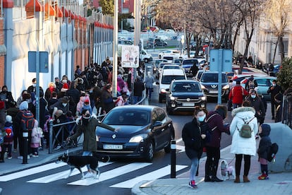 Niños de infantil y primaria entrando a clase entre vehículos en el colegio Sagrado Corazón Padres Capuchinos de Madrid, con la A-42 al fondo. 