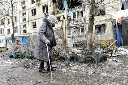 Una anciana camina ayudada por un bastón junto a su edificio, dañado por los bombardeos rusos en Járkov, este martes.