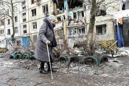 Una anciana camina ayudada por un bastón junto a su edificio, dañado por los bombardeos rusos en Járkov, este martes.