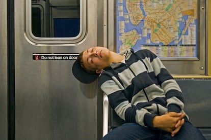 A teenager sleeps in a subway car.