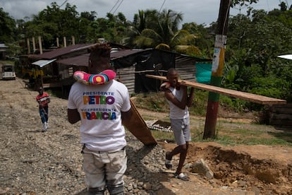 Dos jóvenes cargan tablones de madera en un barrio de las periferias de Timbiquí, el 24 de junio de 2022.