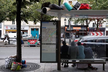 Migrantes esperam debaixo da parada do ônibus durante a evacuação do acampamento improvisado em Paris