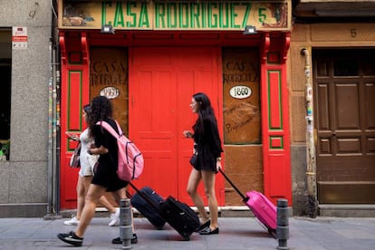 Tres jóvenes turistas llevan sus maletas por la calle de las Maldonadas de Madrid.