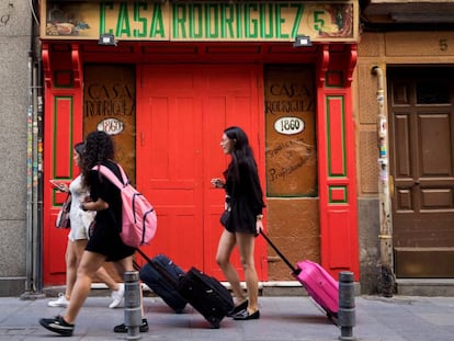 Tres jóvenes turistas llevan sus maletas por la calle de las Maldonadas de Madrid.