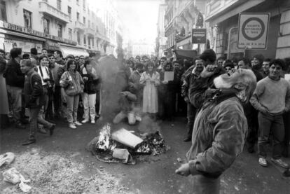 Un grupo de personas observa la quema de una papelera con restos de basura en el centro de Madrid, durante la huelga general del 14-D contra la política económica del Gobierno.