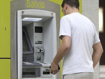 Un hombre saca dinero de un cajero automático de Bankia.