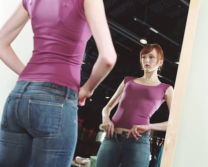Young woman trying on jeans in front of mirror, low angle view 
