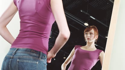 Young woman trying on jeans in front of mirror, low angle view